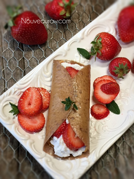spreading peanut butter, coconut whip, and fresh strawberries inside the raw vegan fresh Homemade Strawberry Banana Crepes