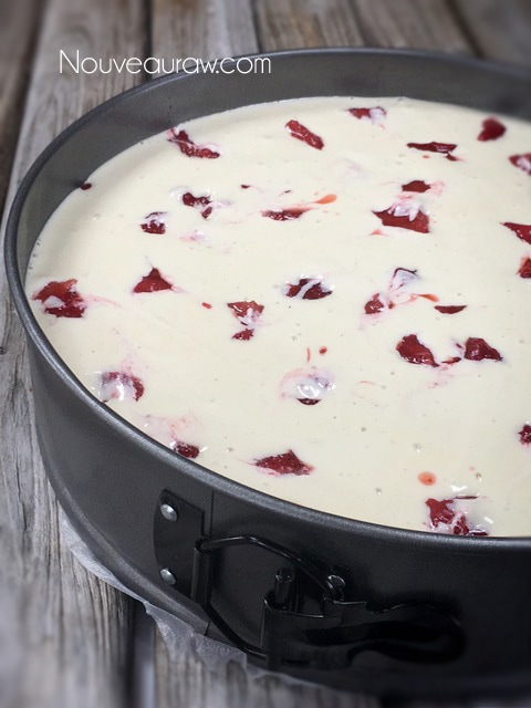 a picture of the pan filled with cheesecake batter and fresh strawberries