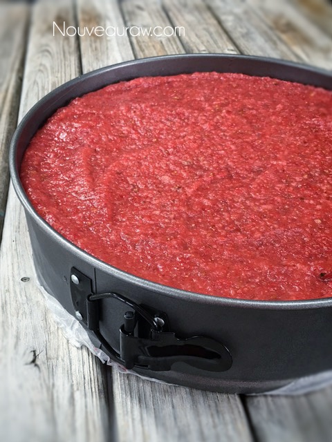 a layer of fresh strawberry puree being added to the cheesecake top