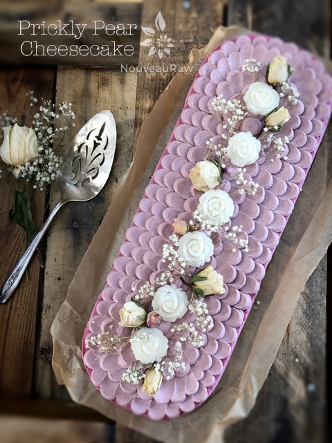 a close up raw vegan Prickly Pear Cheesecake decorated with coconut roses and baby breath