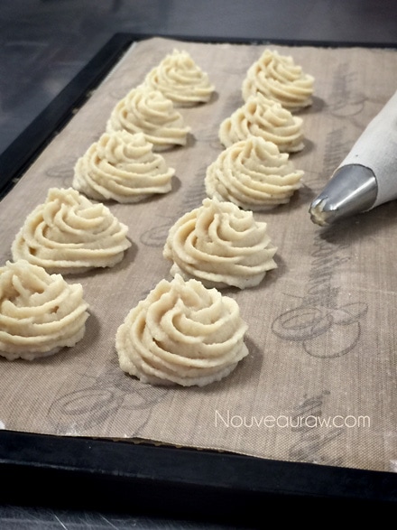 piping the Cashew Lemon Spritz Cookies on a dehydrator tray