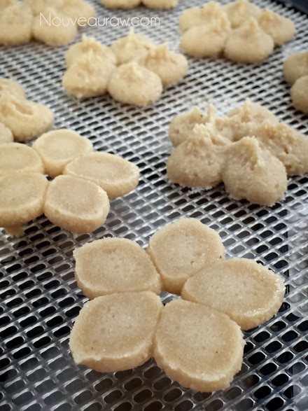 a close up of creating different shapes using a cookie press to make raw vegan gluten free Cashew Lemon Spritz Cookies 