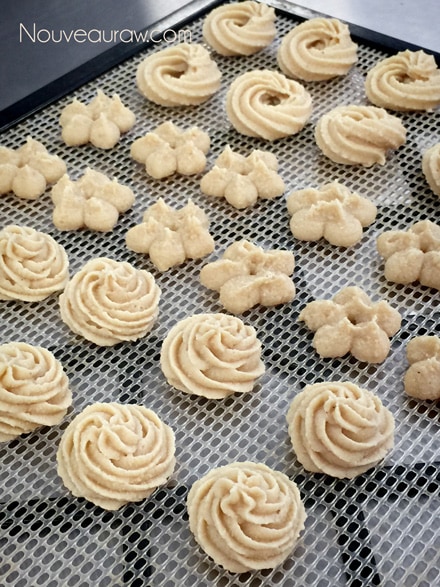 creating different shapes using a cookie press to make raw vegan gluten free Cashew Lemon Spritz Cookies 
