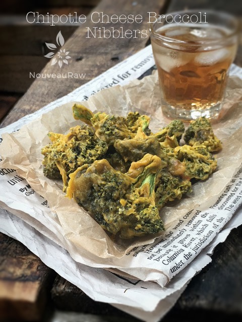 raw vegan Chipotle Cheese Broccoli Nibblers displayed on a newspaper with an ice tea