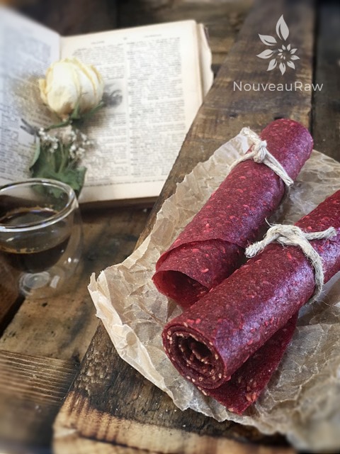 raw sugar free Sherbet-Berry Fruit Leather rolled up on a piece of barn wood served with coffee