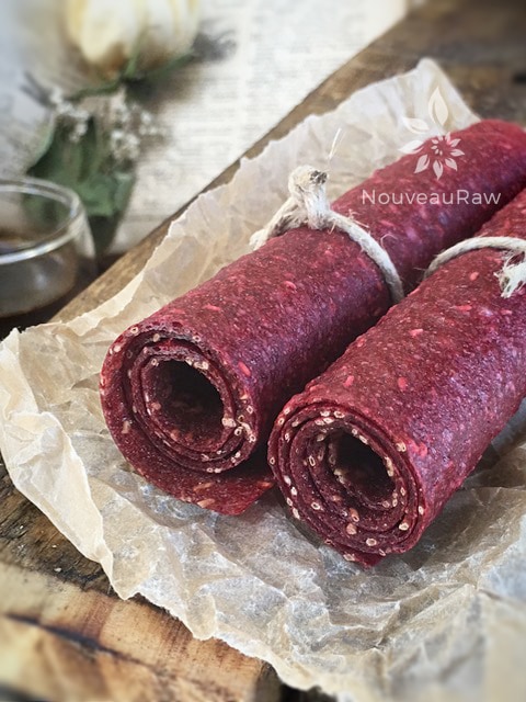 a close up of raw sugar free Sherbet-Berry Fruit Leather rolled up on a piece of barn wood