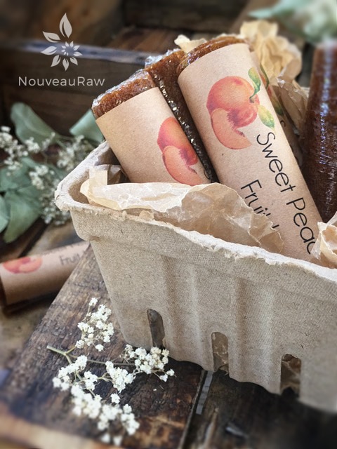 a close up of Sweet Peach Fruit Leather rolled in plastic wrap with a handmade label attached 