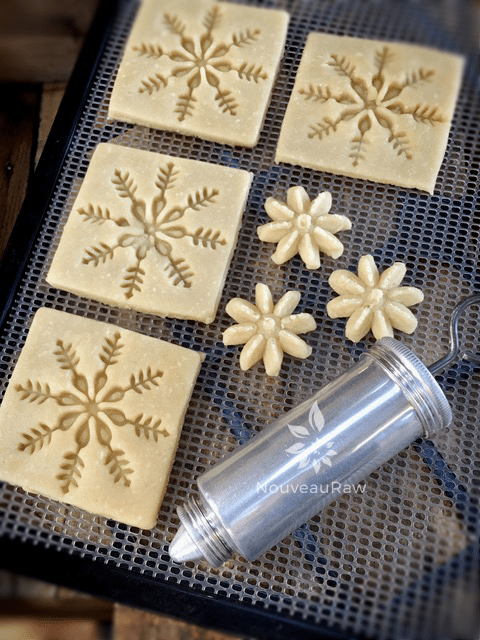 pressing imprints on the raw vegan Christmas Butter Spritz Cookies 