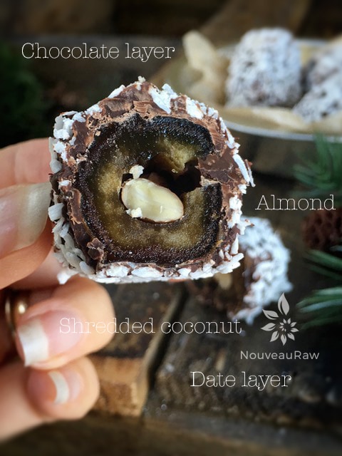 a close up of raw vegan Chocolate Covered Almond Stuffed Dates displayed on barn wood