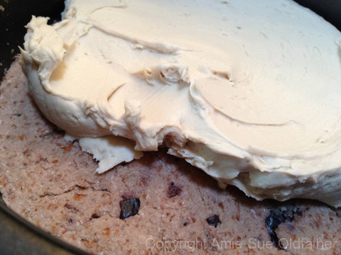 adding the frosting between layers of raw vegan gluten-free Cherry Chip Layer Cake 