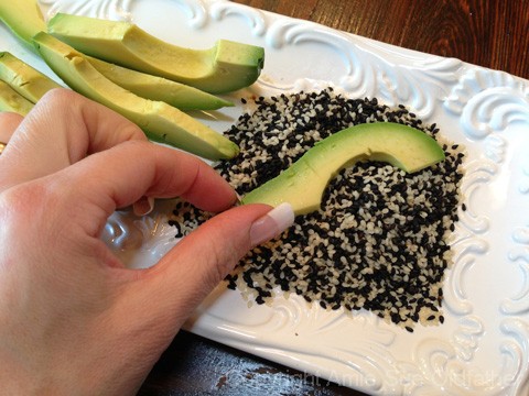 coating the avocado with sesame seeds