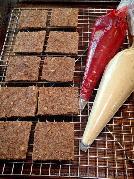 getting ready to pip the filling into the raw vegan gluten free Peanut Butter and Jelly Cracker Sandwiches 