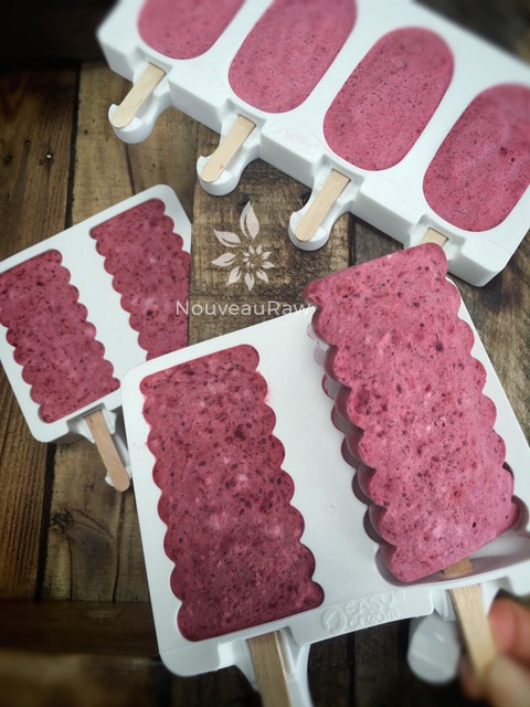 raw vegan Pomegranate and Cherry Popsicles coming out of the molds