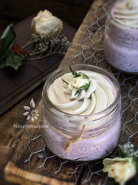 raw strawberry pudding in a mason jar topped with lemon cream that is dairy free
