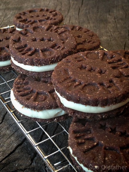 a stack of raw vegan gluten free Chocolate and Cream Sandwich Cookies while displayed on a wooden table