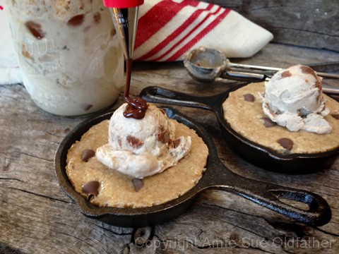 drizzling chocolate sauce over the raw vegan gluten-free Chocolate Chip Skillet Cookie served with Ice Cream 