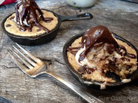 taking a bite from the drizzling chocolate sauce over the raw vegan gluten-free Chocolate Chip Skillet Cookie served with Ice Cream 