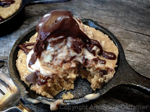 taking another bite from the drizzling chocolate sauce over the raw vegan gluten-free Chocolate Chip Skillet Cookie served with Ice Cream 