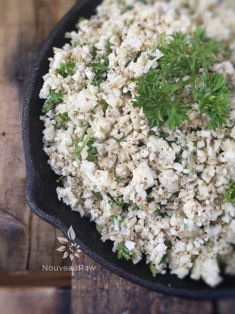 a close up of raw vegan Savory Seeded Cauliflower "Rice" served in a cast iron skillet