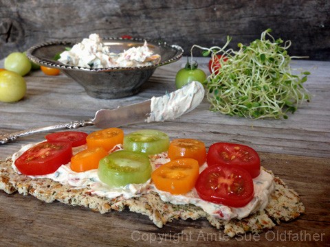 raw vegan Sun Dried Tomato and Basil Cheese served on a raw cracker with cherry tomatoes