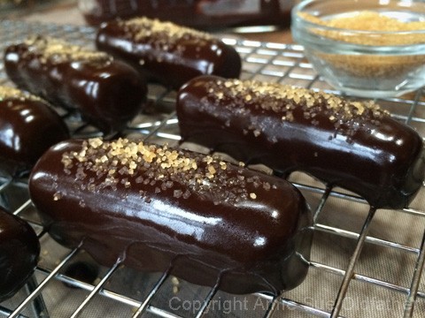 sprinkling raw coconut crystals on top of the raw vegan Chocolate Enrobed Cinnamon Cookie Sticks 