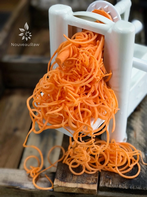 creating noodles out of raw sweet potato noodles in a homemade ceramic bowl