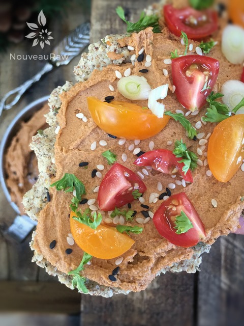 a close up of raw gluten free Crispy Rosemary Flatbread Crackers with human and tomatoes on top