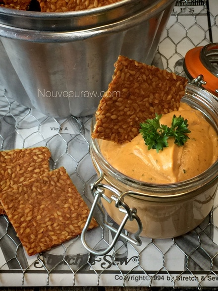 a close up Spicy BBQ Flax Crackers dipped in raw vegan cheese sauce