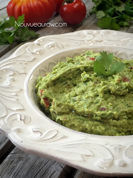 a close up of half the fat Sweet Pea Guacamole served in a white decorative bowl