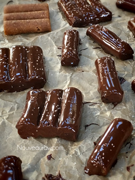 sprinkling salt on the Raw vegan Gluten-Free Salted Honey Nougat Candy Bars in chocolate