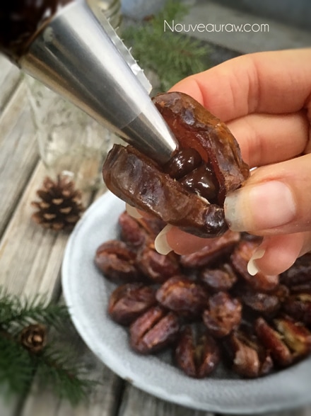close up of Medjool dates sliced open with chocolate being piped in
