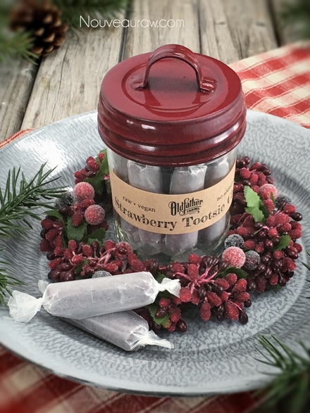 raw vegan Strawberry Tootsie Chews stored in a small mason jar with a red decorative lid