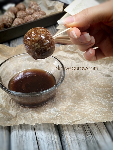 dipping the balls into the coating sauce for the raw vegan gluten-free Chewy Cinnamon Donut Holes 