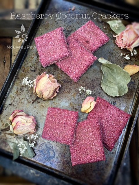 raw gluten-free Raspberry Coconut Crackers on a cookie sheet with dried roses