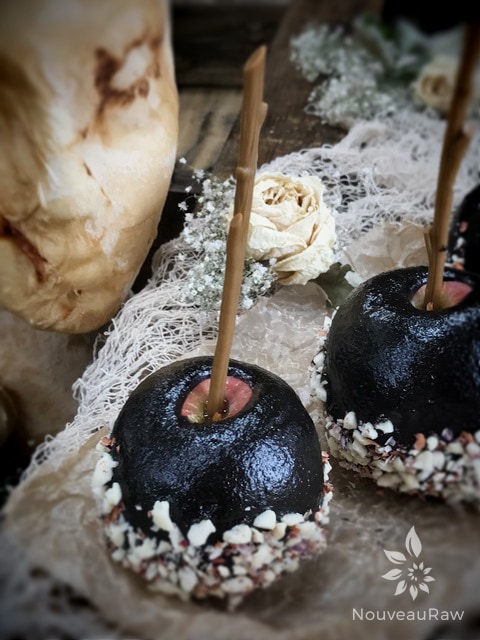 close up of raw vegan Black "Candied" Apples displayed with Halloween props