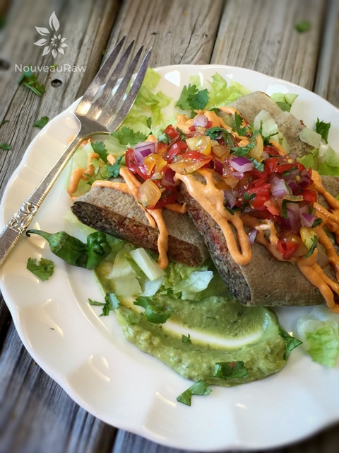 raw vegan "Refried Bean" and "Beef" Burritos on a white plate with guacamole and lettuce