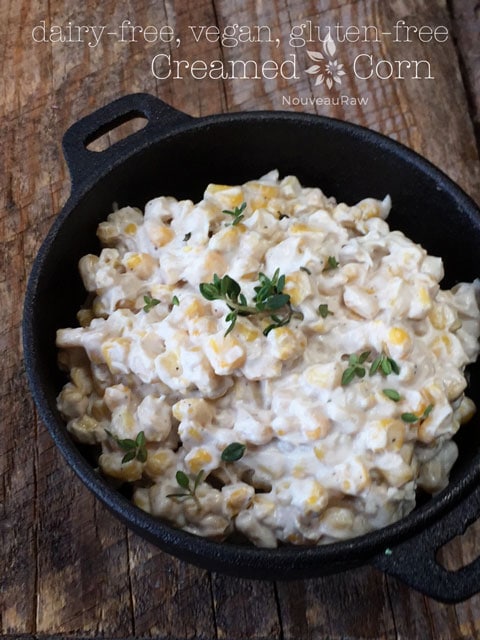 raw vegan creamed corn served in a cast iron dish on a piece of barn wood