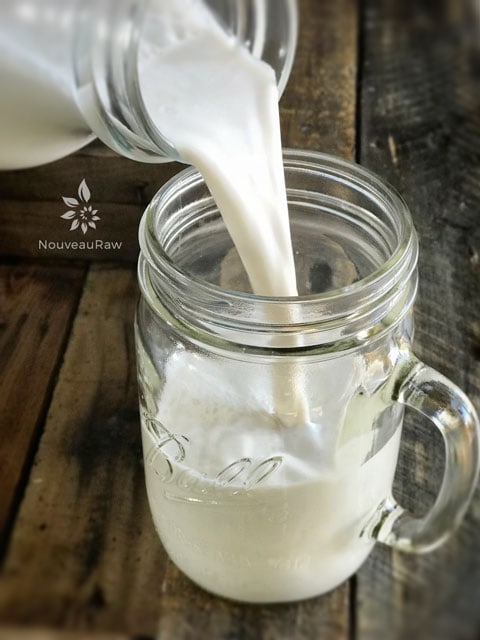 pouring a mug of raw vegan Almond-Sesame-Milk